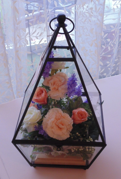 Silk Flower Arrangement - A gorgeous arrangement of Silk Flowers in Glass and Metal Lantern (photo for illustration only as shapes differ).

These can be made to the colour theme of your choice.

We also supply Silk Flowers for home decor and Weddings